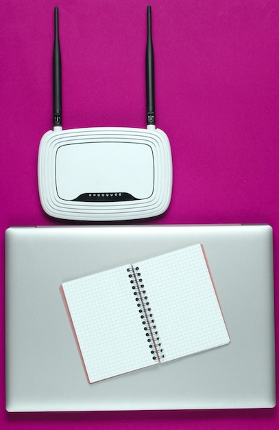 Wi fi router, laptop, pc mouse, notepad on pink background