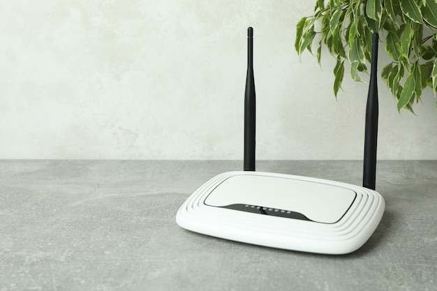 Foto router wi-fi e pianta su un tavolo con texture grigia