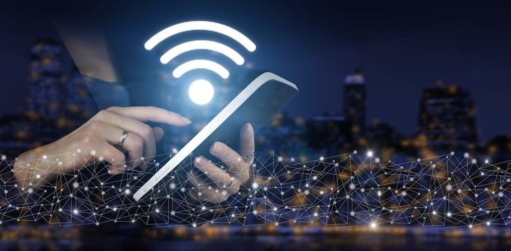 Фотография концепция беспроводной сети wi-fi. вручите сенсорный белый планшет с цифровой голограммой wi-fi подписать на темном фоне размытым городом. бизнес-концепция сетевого подключения и wi-fi в городе.