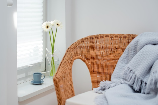 Wicked fauteuil in minimalistisch gezellig wit kamerinterieur Kopje koffie en bloemen op de vensterbank schoonheid en eenvoud van ochtendroutine licht Scandinavisch interieur