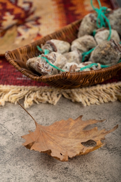 Wicker basket of dried sweet persimmons on stone table.