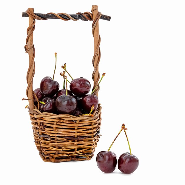 Wicker basket full of ripe sweet cherries on white background