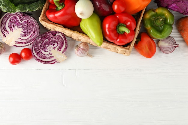 Wicker basket and vegetables on white wooden top viewWicker basket and vegetables on white wooden top view