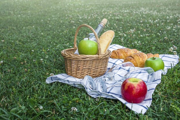 Wicker basket with apples and a bottle of rose wine