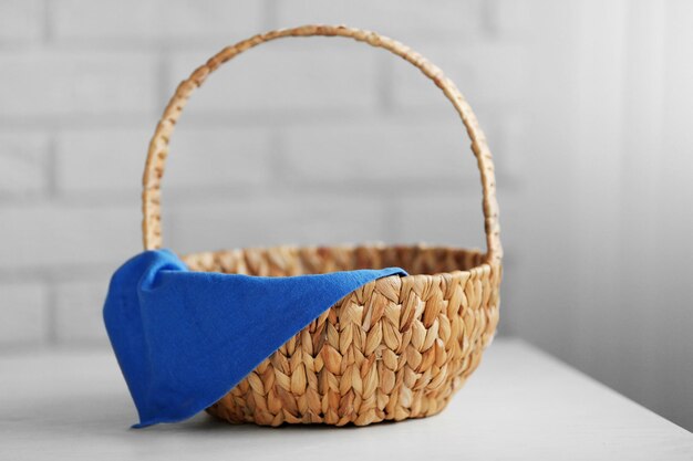 Wicker basket with blue napkin on wooden table closeup