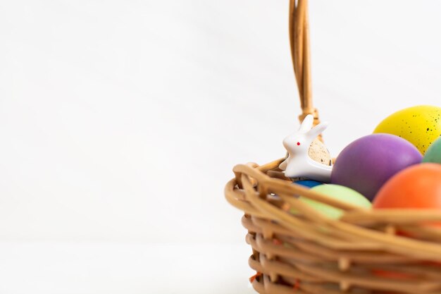 Фото Плетеная корзина с яркими красочными яйцами и текстом счастливой пасхи и цветком