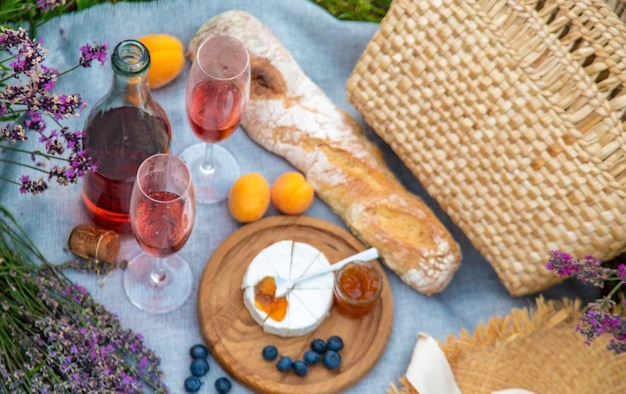 Wicker basket with delicious food for a romantic picnic in a lavender field wine fruits berries Selective focus nature