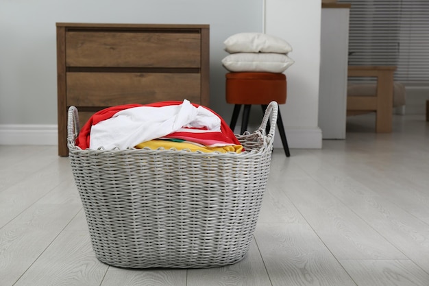 Photo wicker basket with dirty laundry on sofa indoors