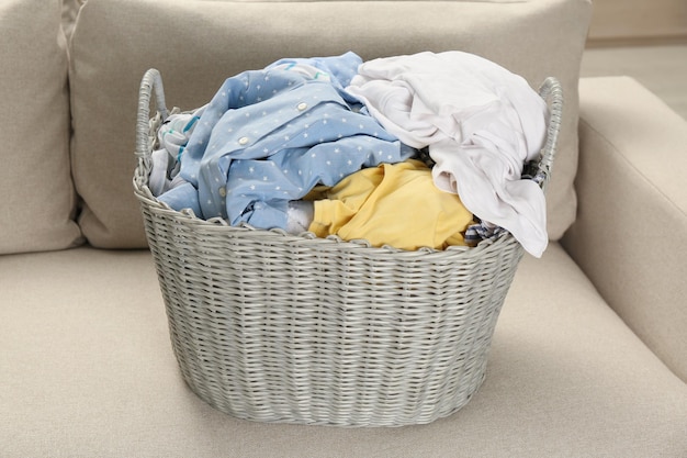 Wicker basket with dirty laundry on sofa in room