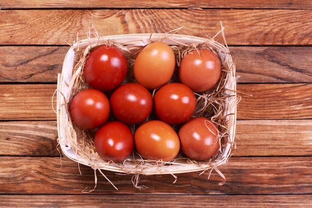 Wicker basket with Easter eggs on wooden table