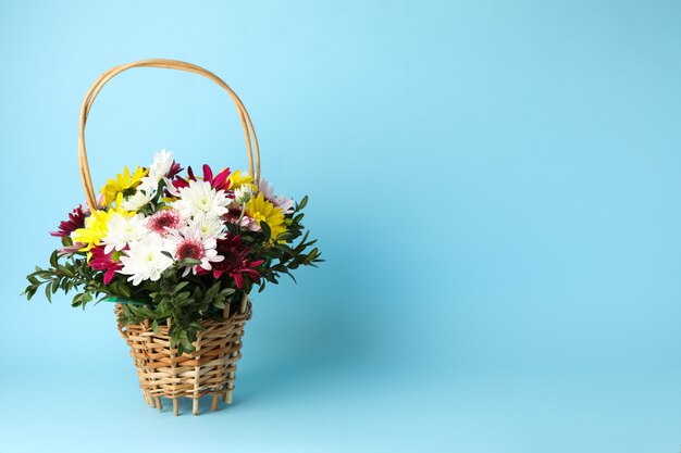 Wicker basket with flowers on blue