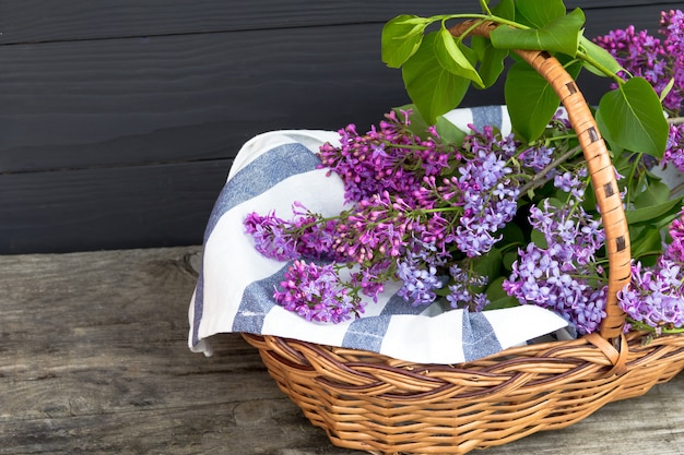 Wicker basket with lilac on wooden table. Free copy space.