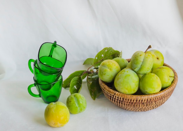 Wicker basket with plums. Light background