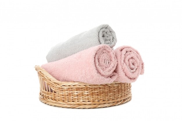 Wicker basket with rolled towels isolated on white
