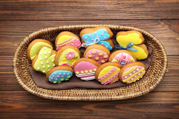 Wicker basket with tasty Easter cookies on wooden background