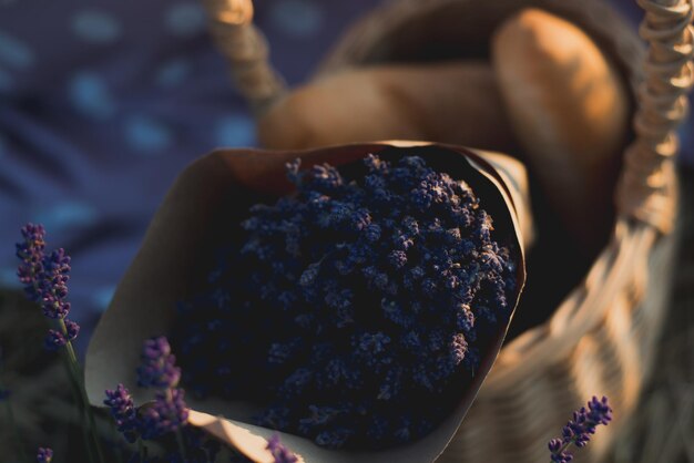 Wicker basket with tasty food and lavender bouquet for romantic picnic in lavender field