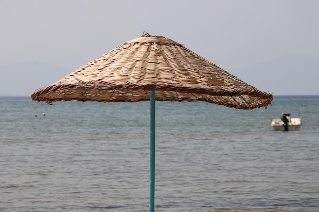 wicker beach umbrella and plastic white sunbed on the beach