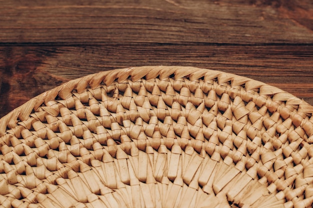 A wicker bowl for decor and fruits stands on a wooden brown table