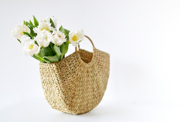 チューリップの花が付いている枝編み細工品のハンドバッグ