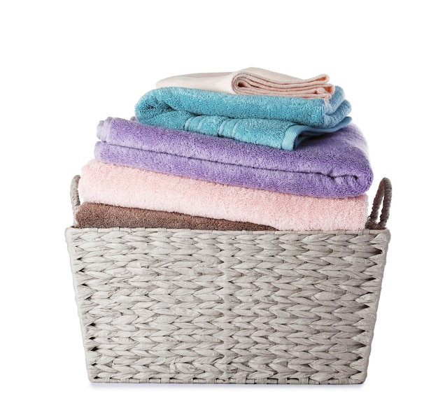 Wicker laundry basket with clean towels on white background