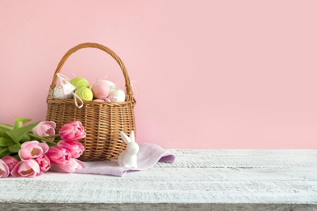 Wicker mand met paaseieren en roze tulpen Lente paas roze achtergrond met ruimte voor tekst