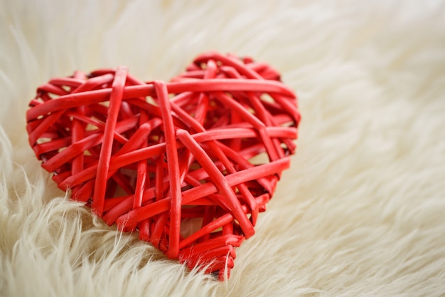 A wicker red heart lies upon us in a white woolen blanket, Valentine's day concept  