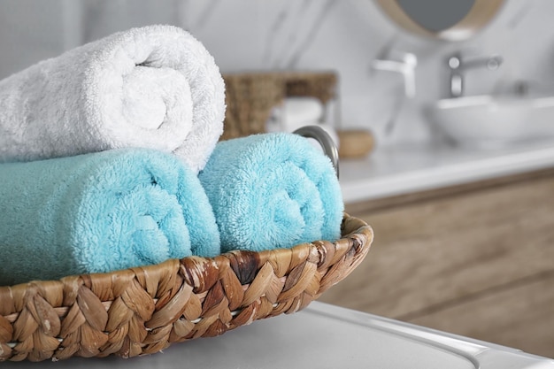 Foto vassoio di vimini con morbidi asciugamani puliti in primo piano del bagno