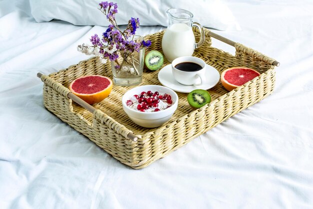 Wicker tray with food and drink on a white bed