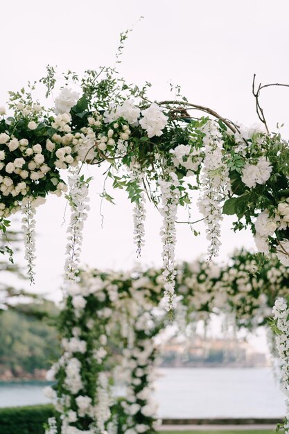 Wicker wedding arch decorated with roses wisteria and green leaves