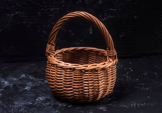 Wicker wooden basket on black abstract background.