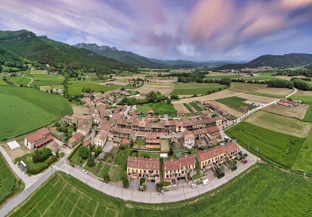 Wide angle lens aerial shot of a small village surrounded by green landscapes at sunset