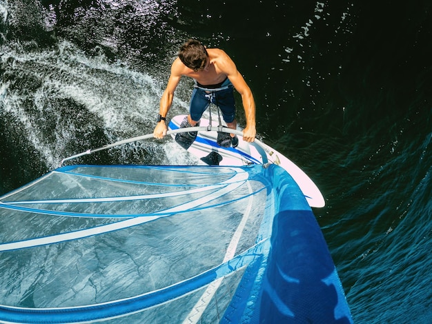 Wide-angle opname van een volwassen man die windsurft op het meer Wallersee Oostenrijk