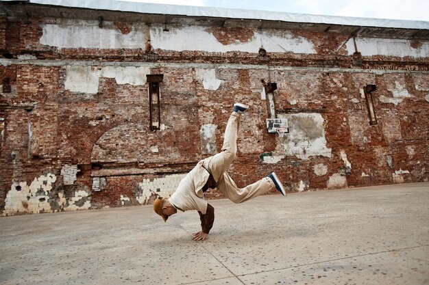 Foto colpo grandangolare del giovane che fa le verticali di breakdance all'aperto nello spazio della copia dell'ambiente urbano squallido