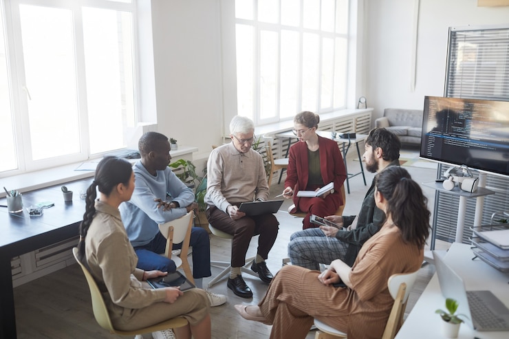 Photo wide angle view at contemporary diverse business team sitting in circle during strategy meeting, focus on senior man in center, copy space