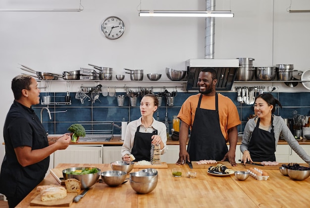 Wide angle view at female chef instructing people during
cooking class in kitchen copy space