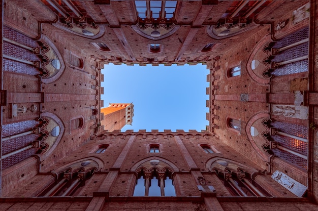 Wide angle view from the courtyard of Palazzo Pubblico to the famous Torre del Mangia. Siena, Tuscany, Italy