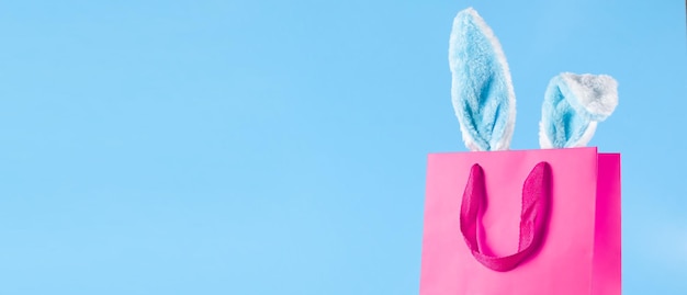 사진 파란색 배경에 넓은 배너 부활절 구매 및 토끼 귀가 있는 휴가 선물 가방 판매를 위한 온라인 쇼핑 개념