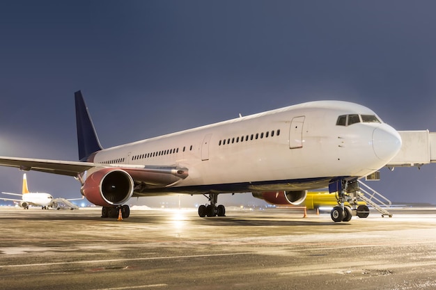 Wide body passenger aircraft at the airport apron at winter night