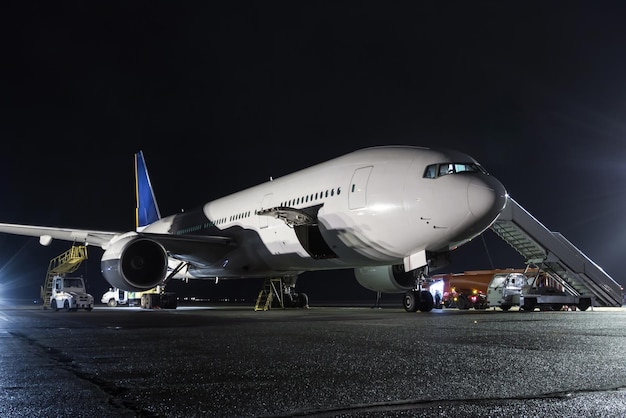 夜の空港エプロンにエア階段を備えたワイドボディ旅客機。飛行機のグランドハンドリング