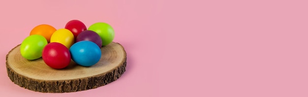 写真 ワイド イースター バナー多色の卵は木の板に横たわってピンクの背景コピー スペース