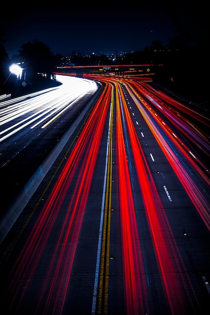 A wide highway with abstract bright traffic light trails at night, vertical background