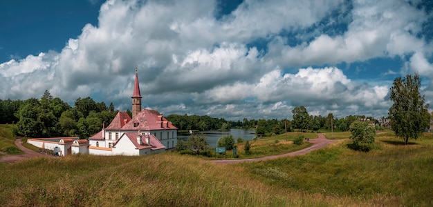 A wide panorama of the beautiful natural landscape. Old castle, blue sky and white fluffy clouds at the sunny summer day. Gatchina. Russia.