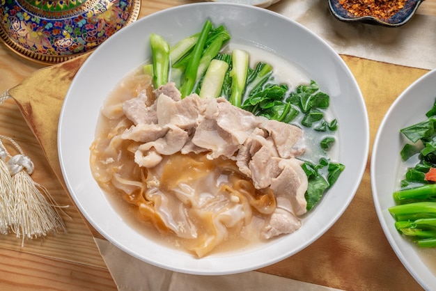 Wide Rice Noodles with pork and kale in Gravy Sauce Served with chili powder and sugar