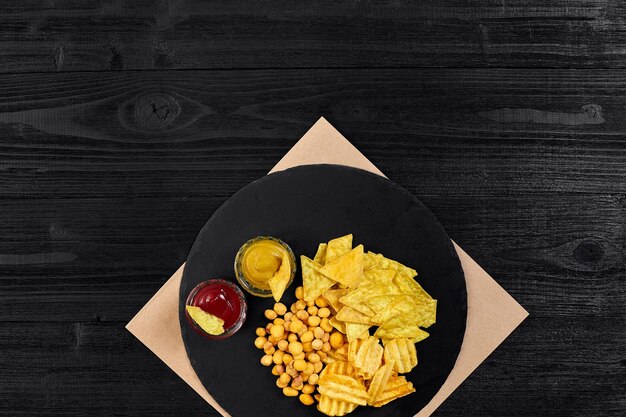 Wide selection of snacks for beer with different sauces on parchment top view