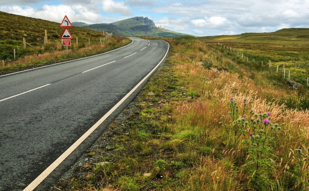 Un'ampia ripresa di strade vuote, curve, dossi e riduzione della velocità ora firma con la montagna old man of storr sullo sfondo. isola di skye, scozia, regno unito.