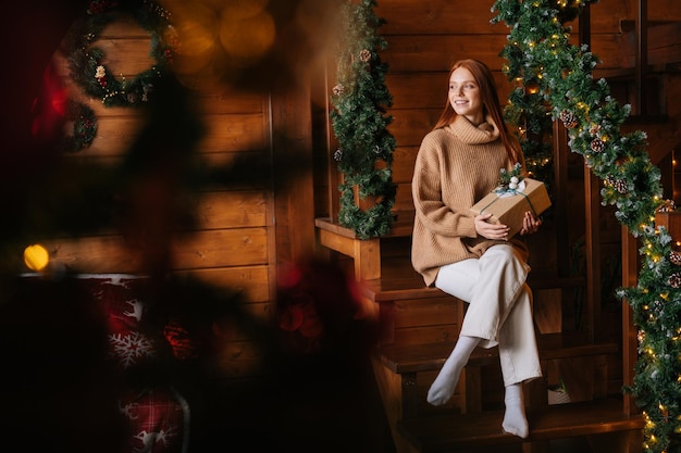 Wide shot of smiling redhead woman happily holding present box in hand received for Christmas