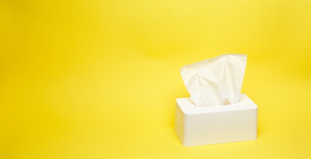 Wide shot of white napkin holder on minimalistic yellow background