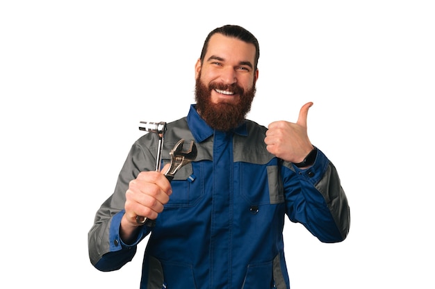 Photo wide smiling ready to work handyman is holding some tools and a thumb up