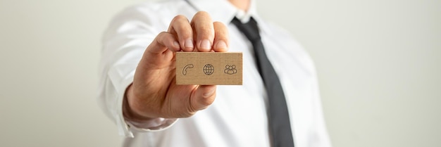 Фото Широкое представление изображения бизнесмена, представляя визитную карточку с контактами и информационными значками на нем.