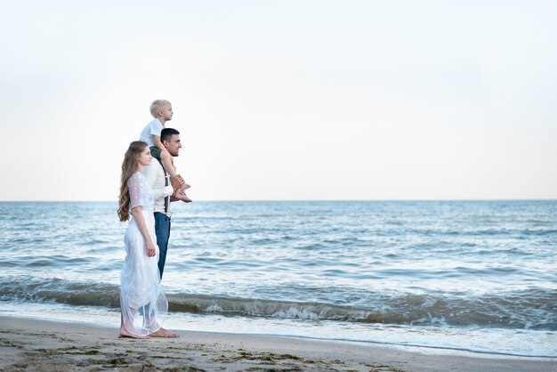 Wide view of young family walking in the sea. Happy childhood and parenthood concept.